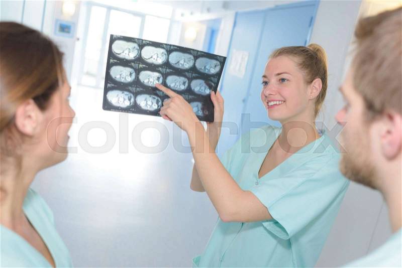 Group of happy doctors looking to and discussing x-ray, stock photo