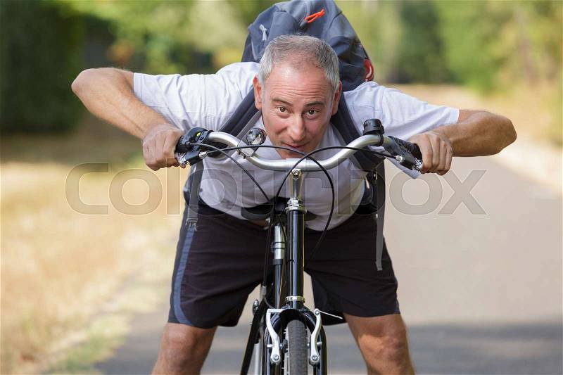 Cheerful middle aged man on a bike outdoors, stock photo
