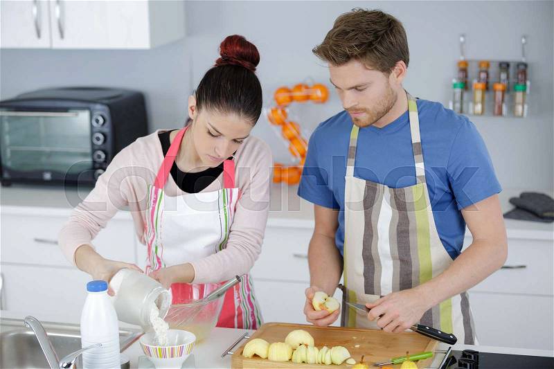Young smiling couple cooking pie at the kitchen at home, stock photo