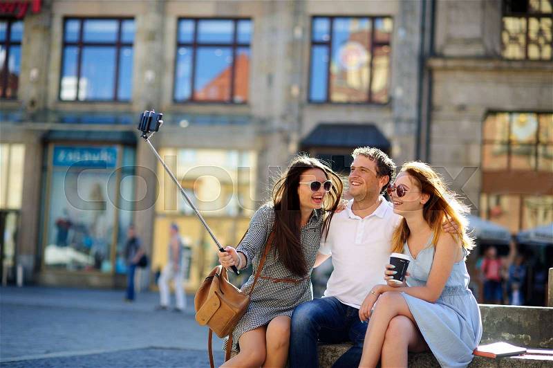 Company of young friends is photographed in the city square. Everyone has a great mood. Sunny summer day, stock photo