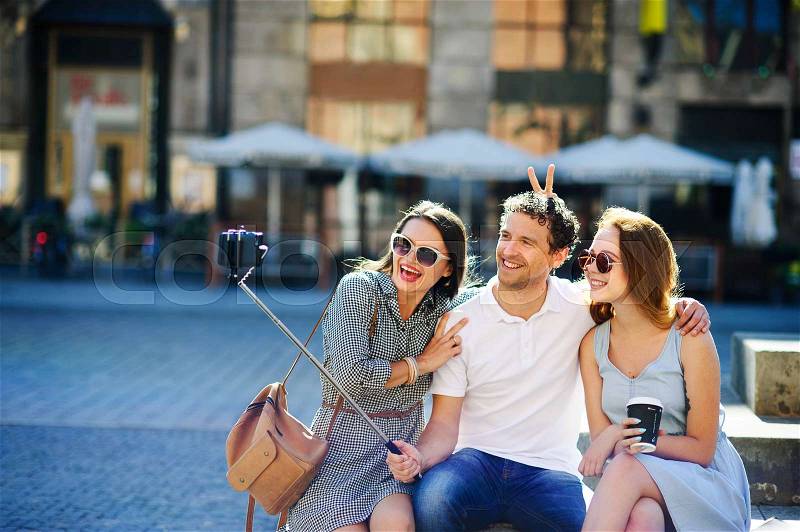 Company of young friends is photographed in the city square. Everyone has a great mood. Sunny summer day, stock photo