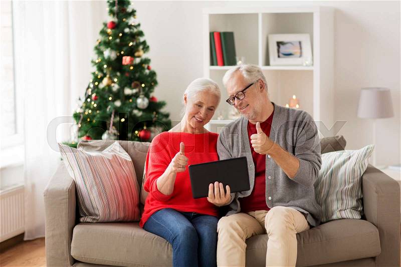 Christmas, holidays, communication and people concept - happy smiling senior couple with tablet pc computer having video chat at home, stock photo