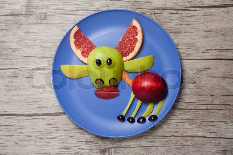 Funny fruit deer made on plate and wooden background, stock photo