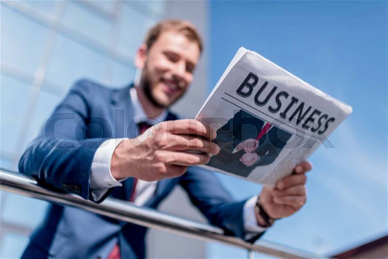 Selective focus of businessman with business newspaper standing at office building, stock photo