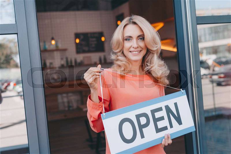 Attractive middle aged small business owner holding sign open and smiling at camera , stock photo