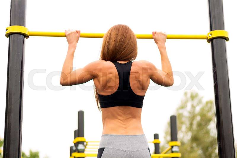 Fit woman exercising outdoors, healthy lifestyle and exercise concept. Pullups, stock photo