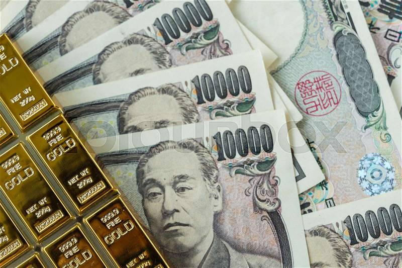 Gold bullion ingot and pile of japanese yen banknotes as financial safe haven or investment concept, stock photo