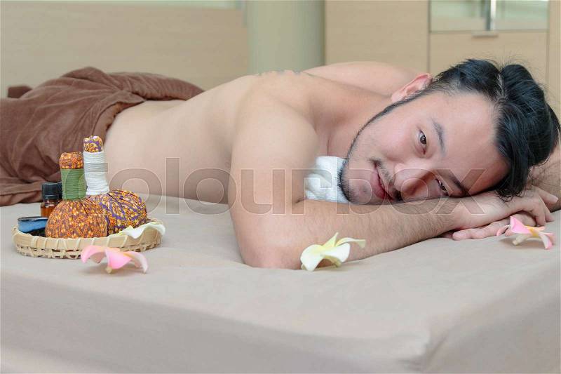 Happy Asian man lying on the massage table and smiling, spa concept, stock photo