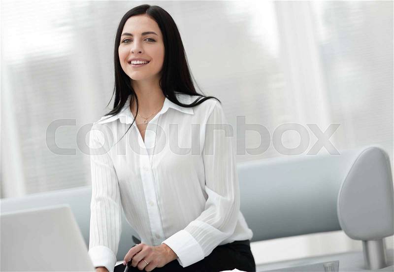 Portrait of a successful young woman sitting at a desk on a blurred background. . business concept. business background, stock photo