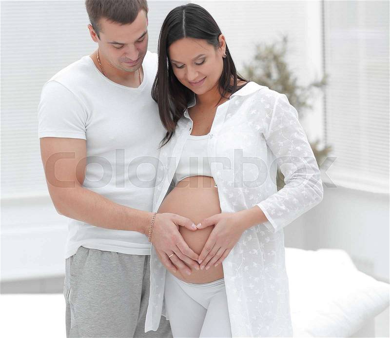 Husband and pregnant wife with folded hands in the shape of a heart on his tummy.concept of family, stock photo