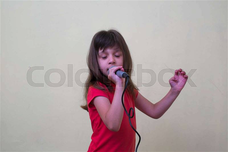 Girl with a microphone. little girl with a microphone. cute little girl singing with a microphone. karaoke. girl sings joyfully. girl singer. the little singer, stock photo