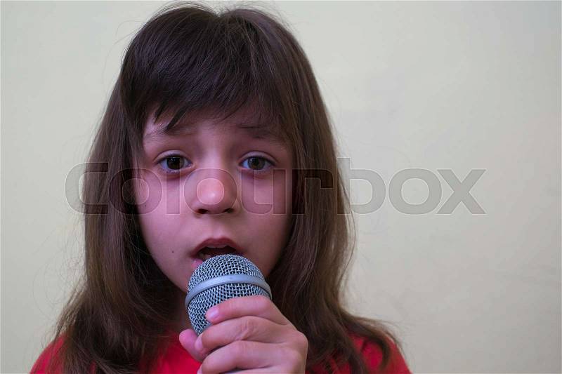 Girl with a microphone. little girl with a microphone. cute little girl singing with a microphone. karaoke. girl sings joyfully. girl singer. the little singer, stock photo