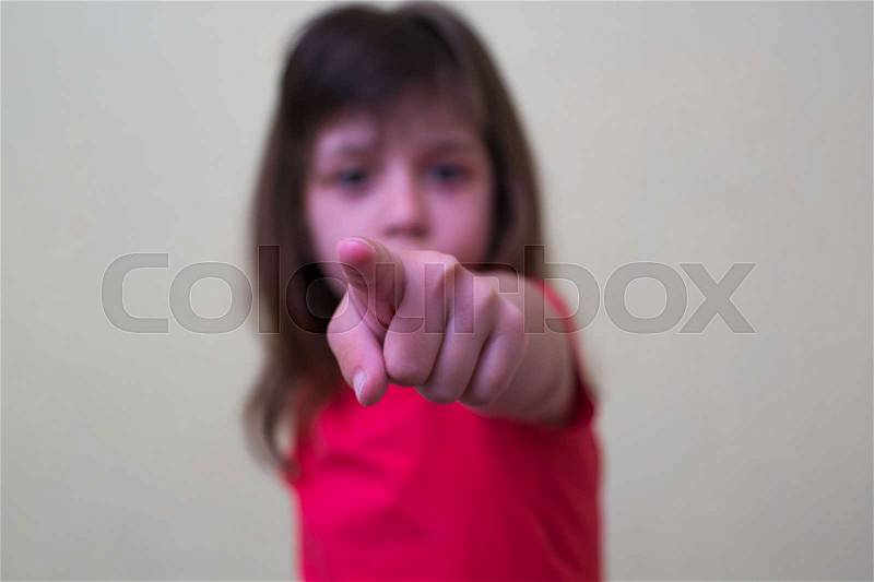 Child pointing with finger, light background, stock photo