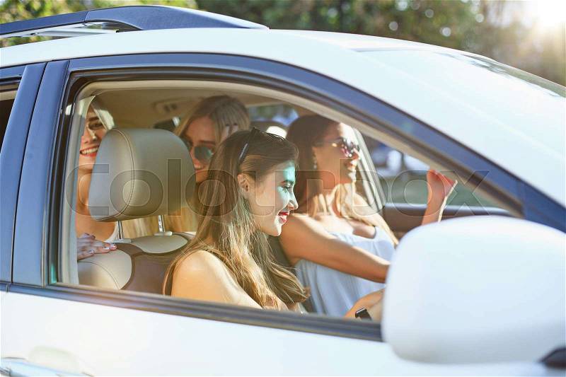 The young women in the car sitting and smiling outdoor. The lifestyle, travel, adventure and female friendship concept, stock photo
