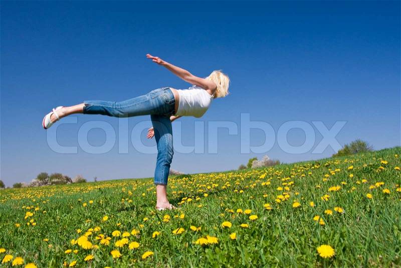 Female practising yoga on a flowery meadow, stock photo