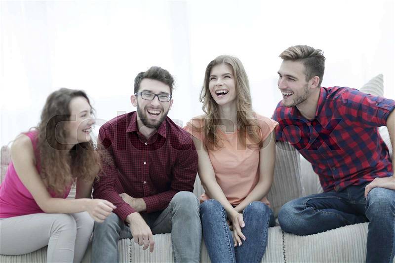 Group of cheerful young people sitting on the couch in the living room, stock photo