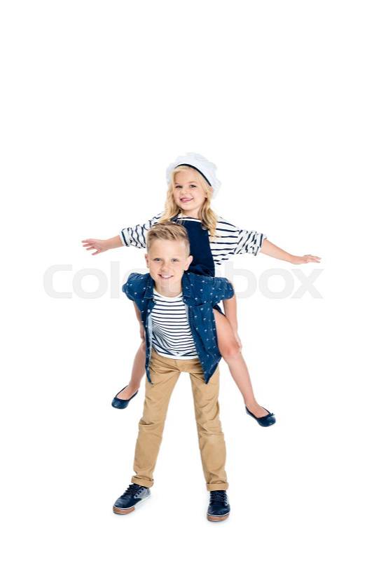 Happy boy piggybacking adorable little sister with open arms isolated on white, stock photo