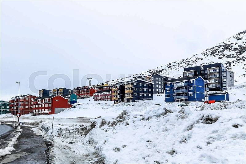 Winter street and row of colorful Inuit houses on the slope of snow mountain in Nuuk, Greenland, stock photo