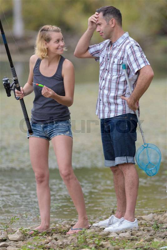 Couple fishing in the pond using a fishing rod, stock photo