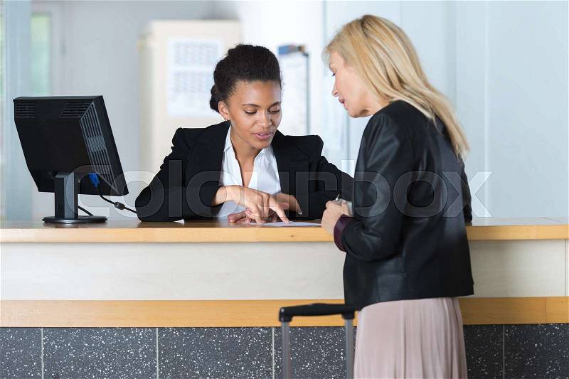 Beautiful girl at the reception of a hotel checking in, stock photo