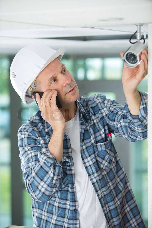 Mature male technician installing camera on the phone, stock photo