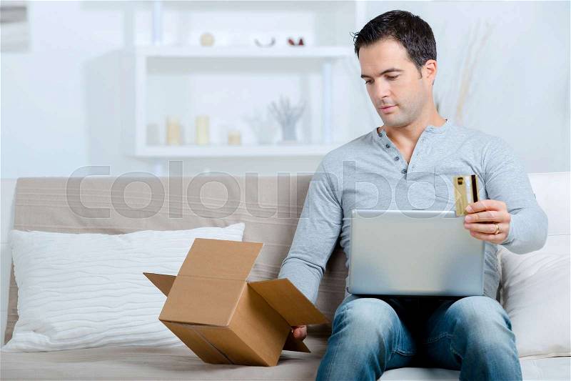 Man in house buying online, stock photo