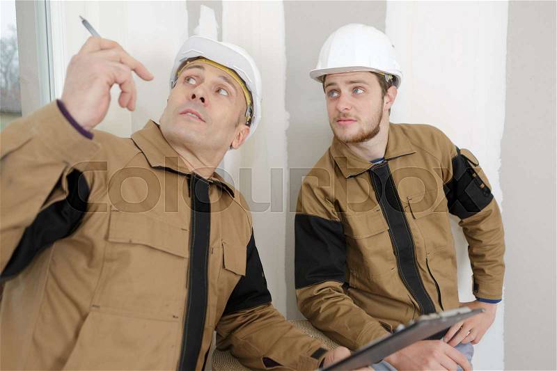 Mason manager giving instructions to a helper, stock photo