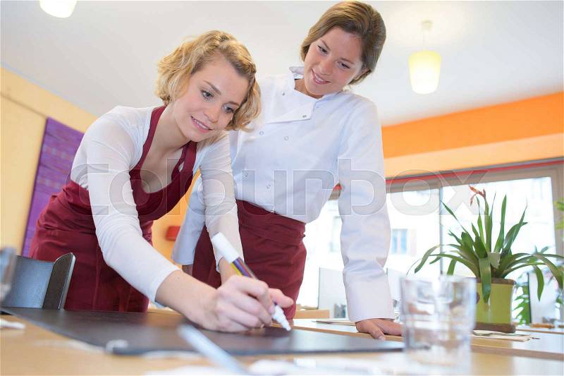 Young waitresses writing at a restaurant board, stock photo