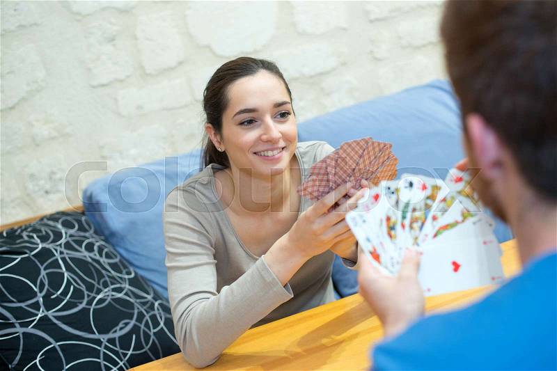 Happy couple playing cards at home, stock photo