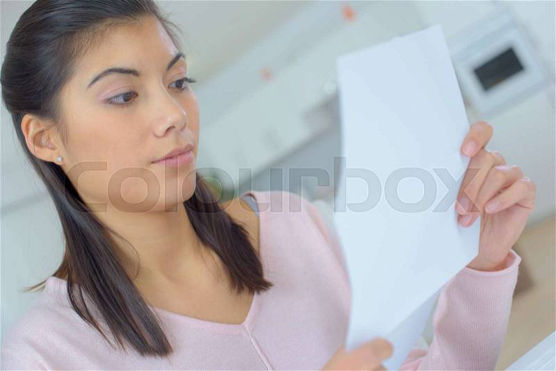Woman on the couch reading letter, stock photo