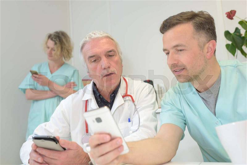 Doctor showing mobil phone to doctor, stock photo