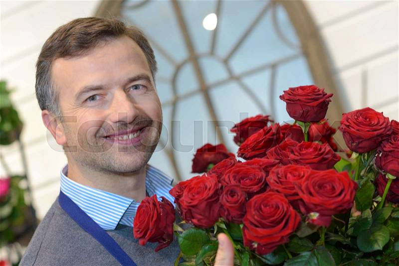Male florist holding a pot of red roses, stock photo