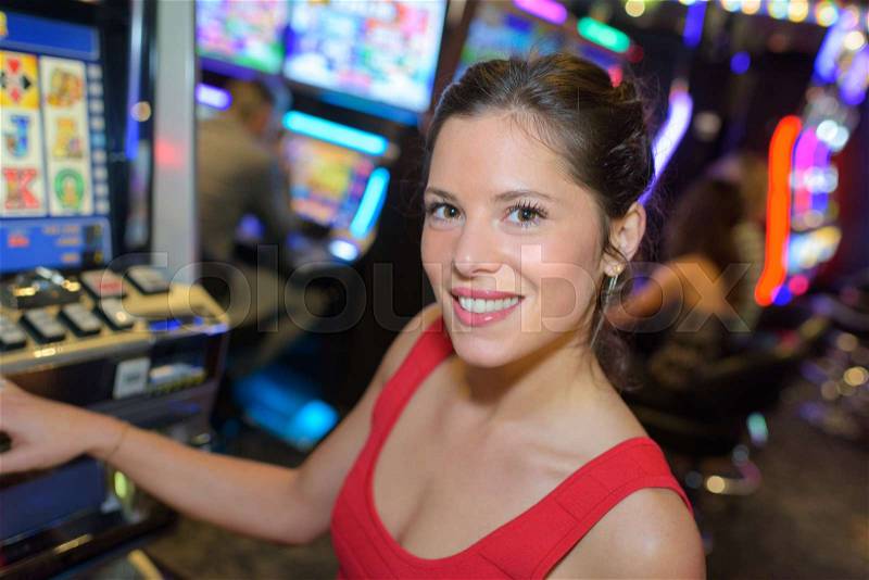 Happy woman next to a slot machine, stock photo