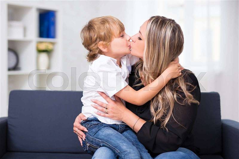 Family pand love concept - young mother kissing her cute little son at home, stock photo