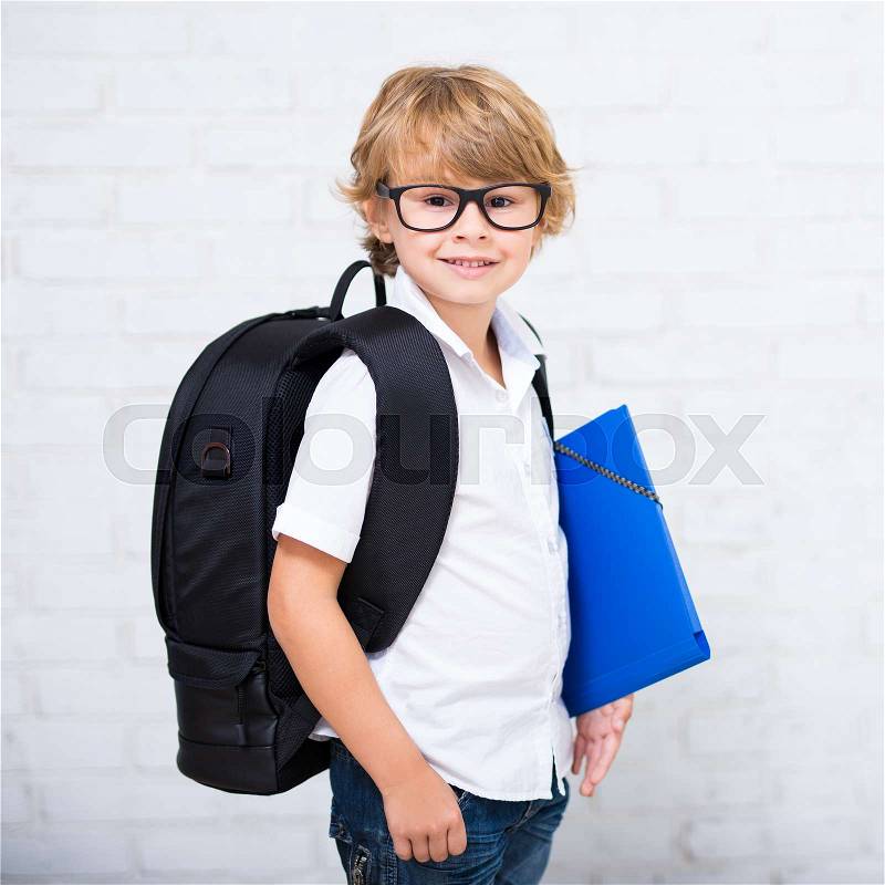Portrait of cute little school boy in glasses with backpack, stock photo