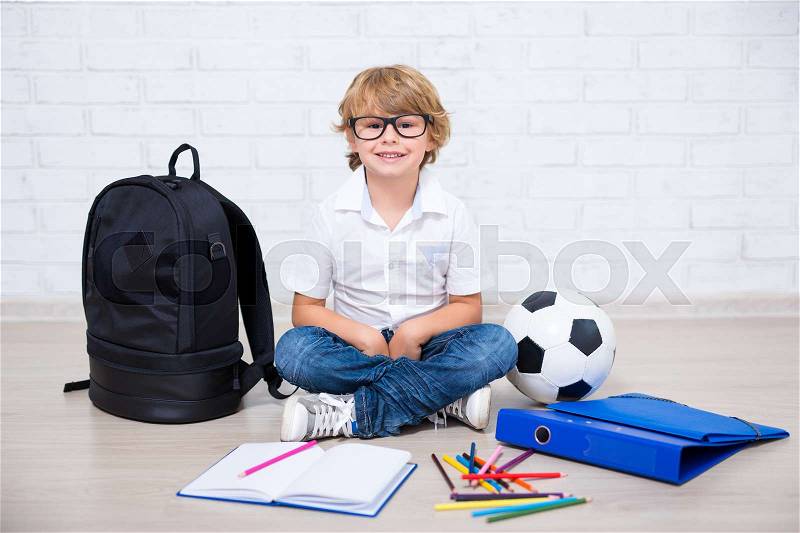 Portrait of little school boy in glasses doing homework at home, stock photo