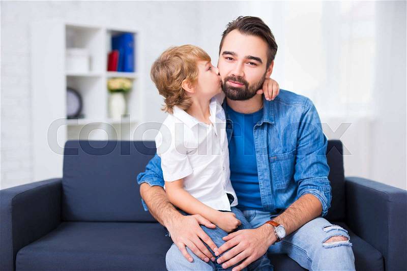 Family and love concept - little son kissing his father at home, stock photo