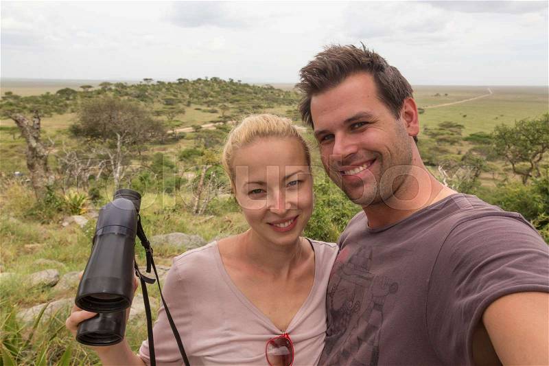 Casual adult couple taking selfie on african wildlife safari in Serengeti national park, Tanzania, Africa, stock photo
