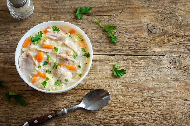 Chicken and Wild Rice Soup. Homemade fresh creamy soup with chicken, vegetables and wild rice in white bowl, copy space, stock photo