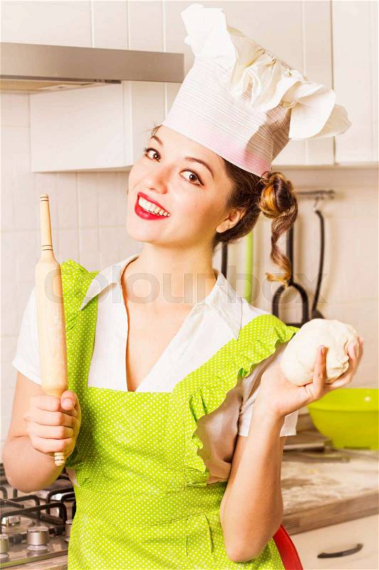 Smiling young chef in chef hat cooking dough in white kitchen room, stock photo