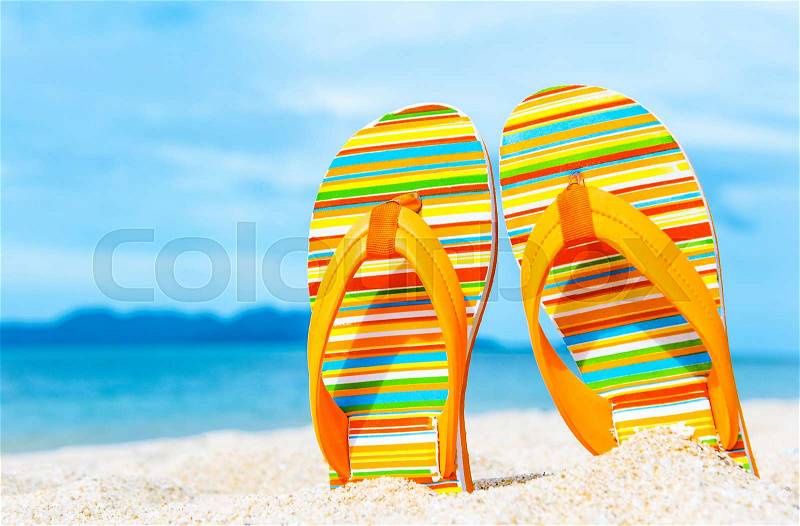 Colorful flip flops on the sandy beach. Vacation concept, stock photo