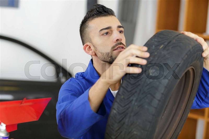 Auto mechanic choose tire for car at a tire store, stock photo
