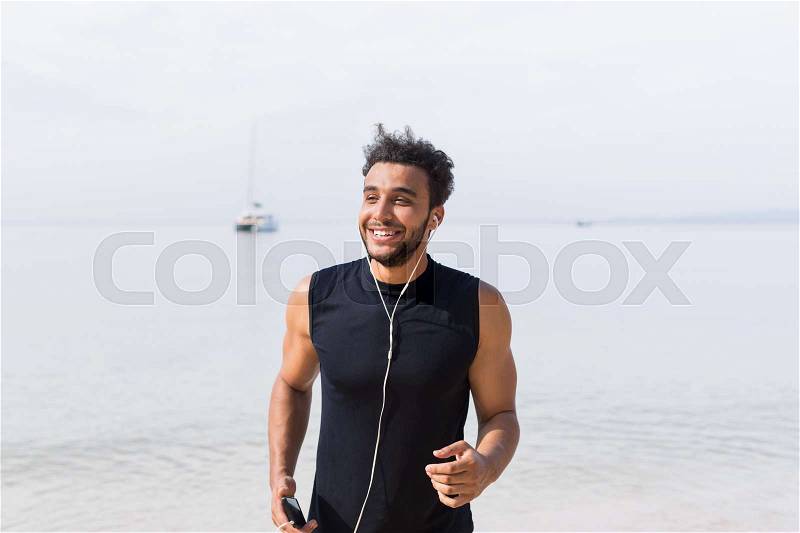 Young Hispanic Man Runner Happy Smiling On Beach Jogging On Seaside Male Latin Sport Fitness Training Outdoors Healthy Lifestyle Concept, stock photo
