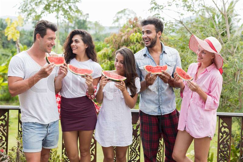 Happy Young Group Of Friends Eating Watermelon On Summer Terrace In Tropical Forest Mix Race People Communicating Holding Slice Of Water Melon, stock photo