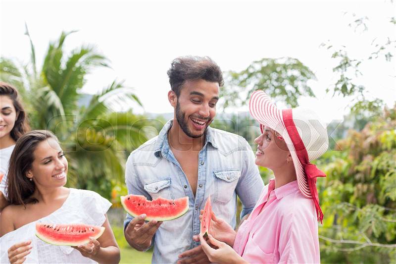 Cheerful Young Group Of Friends Having Fun Together Eating Watermelon On Summer Terrace In Tropical Forest Mix Race People Communicating Holding Slice Of Water Melon, stock photo