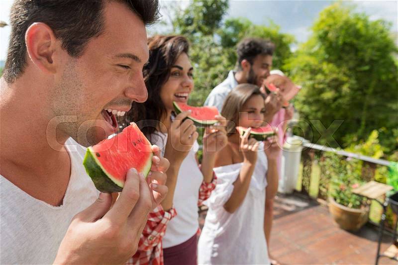 Side View Of Chherful Group Of People Eating Watermelon Together Happy Smiling Friends Having Fun Outdoors, stock photo