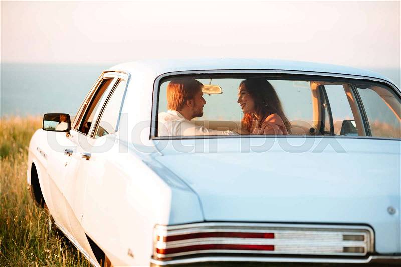 Back view of young pretty couple in car on sunset, stock photo