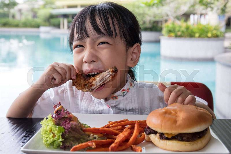 Asian Little Chinese Girl Eating Burger and Fried chicken at Outdoor Cafe, stock photo