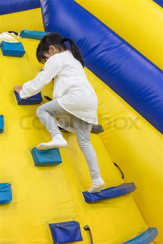 Asian Little Chinese Girl climbing up ramp at Indoor Playground, stock photo