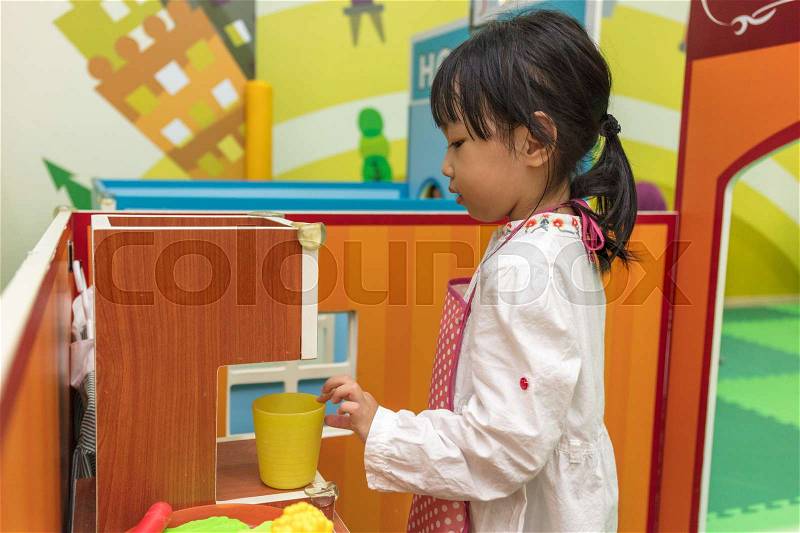 Asian Chinese little girl role-playing at burger store at indoor playground, stock photo